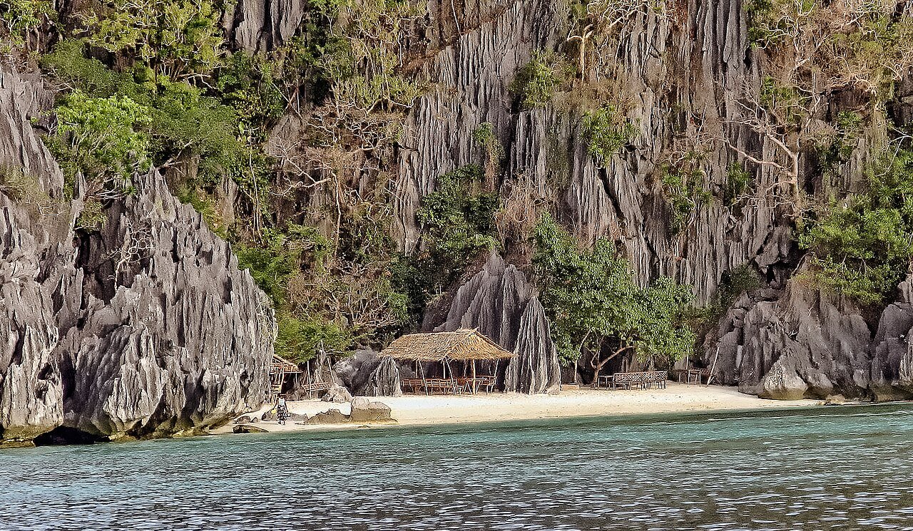Island camping in Coron, a small beach beneath limestone cliffs